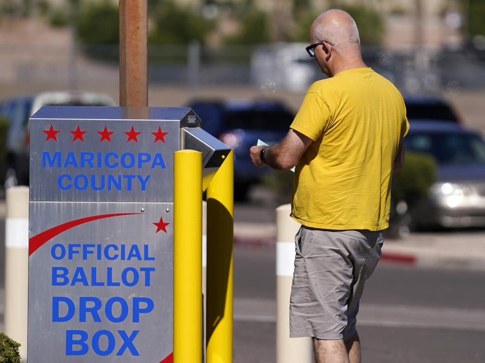 A voter places a ballot in an election voting drop box in Mesa, Ariz., on Friday.