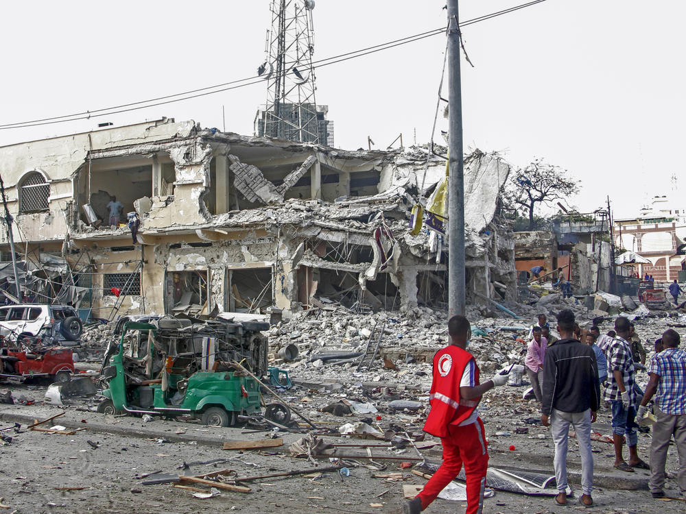 People observe a destroyed building and vehicles at the scene of an attack in Mogadishu, Somalia, on Saturday.