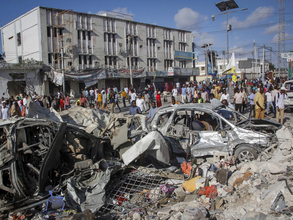 People walk among the destruction at the scene of the weekend's double car bomb attack Mogadishu, Somalia.