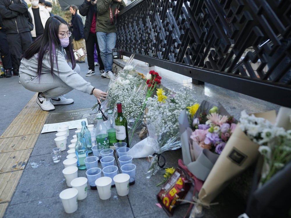 A woman places a bouquet of flowers to pay tribute for victims near the scene of the deadly crowd crush tragedy in Seoul, South Korea.