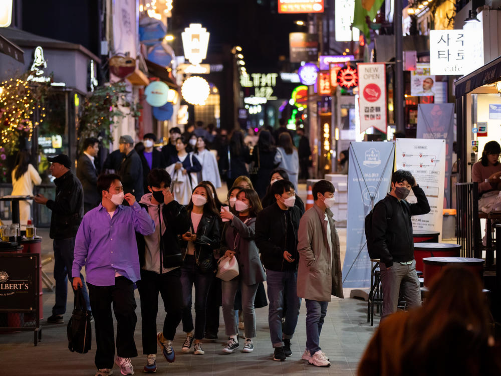 People wearing protective face masks walk through the Itaewon district in Seoul, South Korea, on Friday, April 24, 2020.