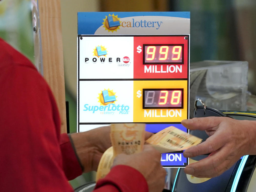 A customer is handed Powerball lottery tickets to purchased at Lichine's Liquor & Deli in Sacramento, Calif., Monday, Oct. 31, 2022. The jackpot for Monday night's drawing soared to $1 billion after no one matched all six numbers in Saturday night's drawing. It's the fifth-largest lottery jackpot in U.S. history.