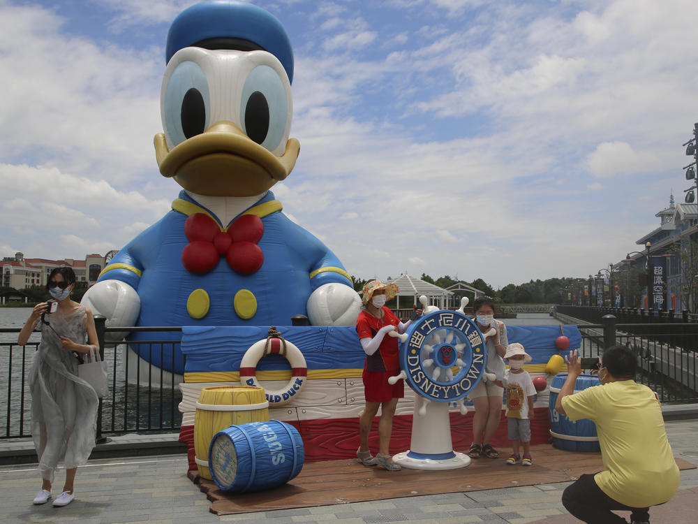Visitors pose for photos outside the Disney Resort theme park in Shanghai in June.