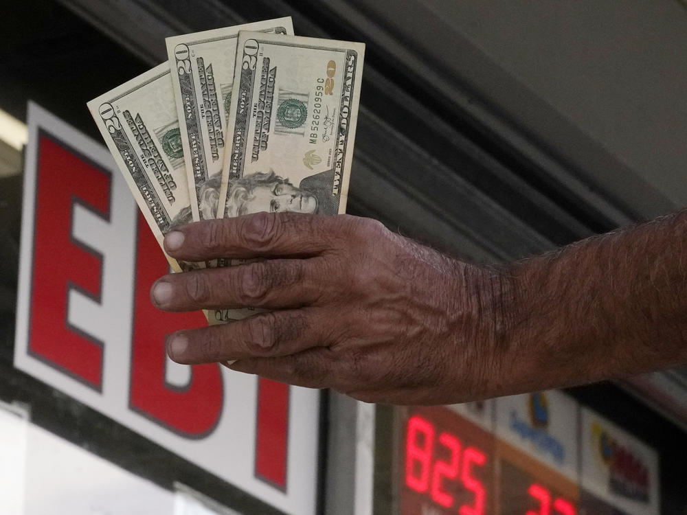Maher Diab holds up cash before buying lottery tickets at Bluebird Liquor, Friday, Oct. 28, 2022, in Hawthorne, Calif. Saturday's jackpot projected winnings of an estimated $825 million is the fifth-highest in U.S. history.