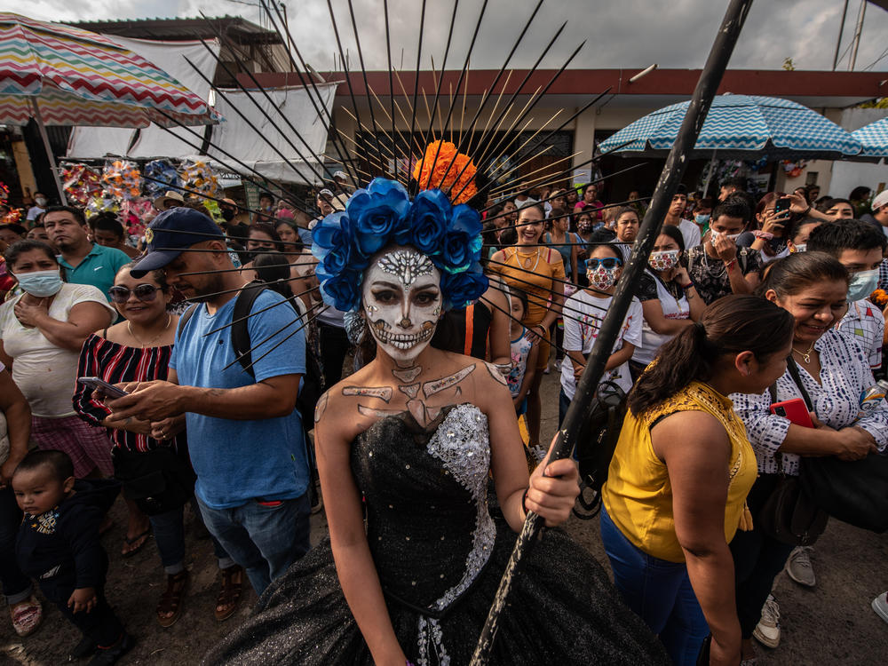 A young woman dressed in Santa Muerte makeup waits outside the pantheon with other participants.