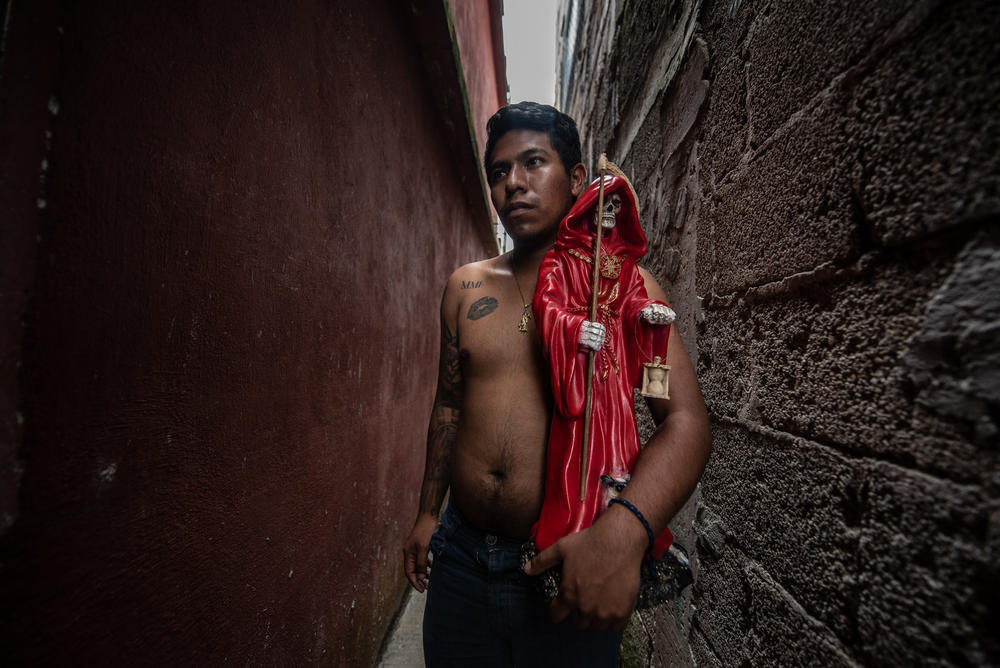 Daniel Guzmán holds a statuette of La Santa Muerte. He is devoted Thanks to his father who initiated him in this belief.