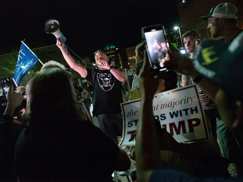 A man shouts into a bullhorn as Trump supporters gather in front of the Maricopa County Elections Department in Phoenix, where ballots were being counted following the 2020 presidential election. Federal officials have warned about violence erupting after this year's election, with experts particularly concerned about the period after Nov. 8.