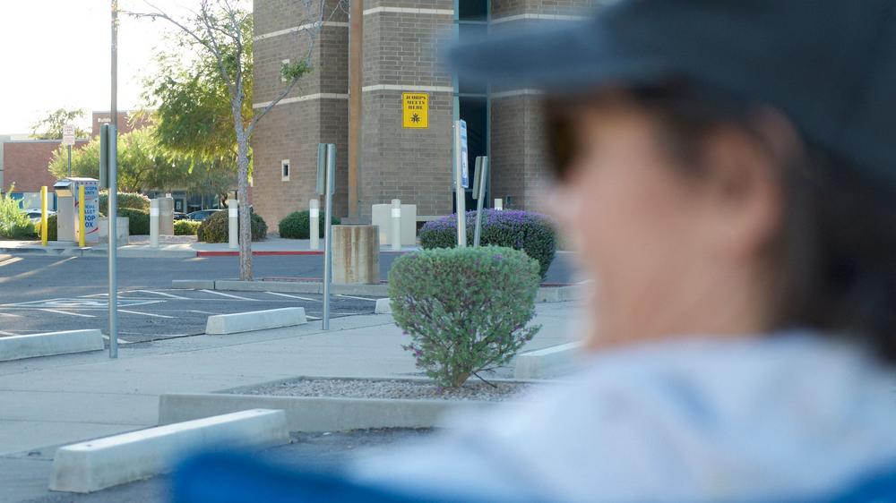 A woman watches a ballot drop box while sitting in a parking lot in Mesa, Ariz., on Oct. 24. The monitoring of drop boxes has raised concerns of voter intimidation.