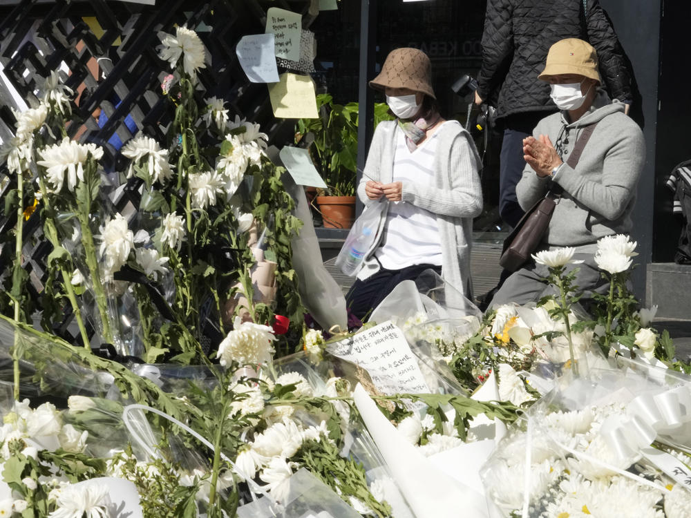 People pray for victims of a deadly accident during Saturday night's Halloween festivities, at a makeshift flower-laying area set up near the scene of the accident in Seoul, South Korea, Wednesday, Nov. 2, 2022.