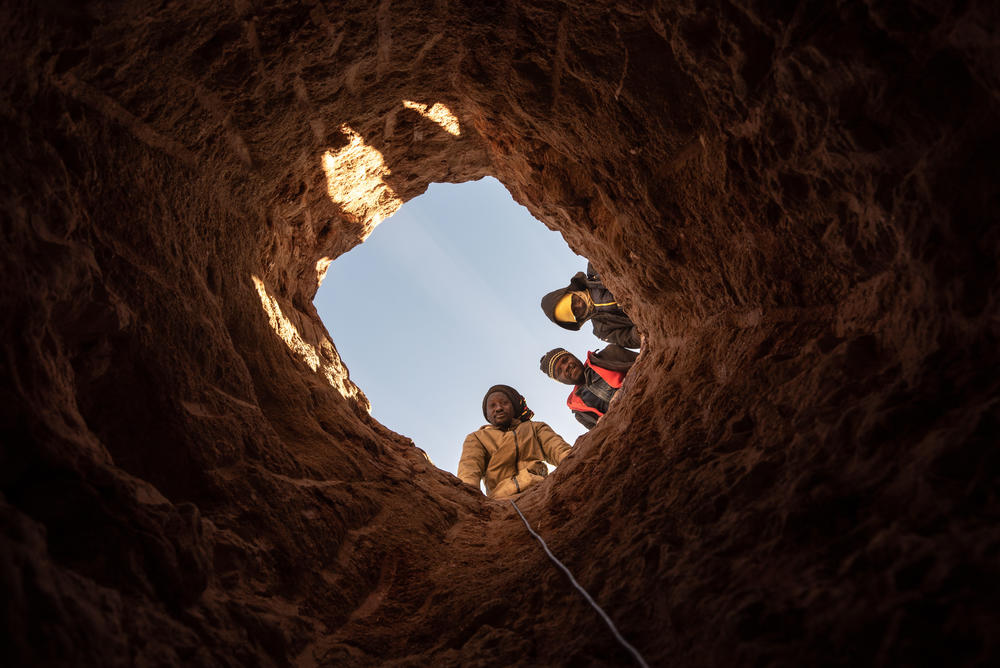 Members of an illegal diamond mining collective look down a mineshaft at the Nuttabooi mine.