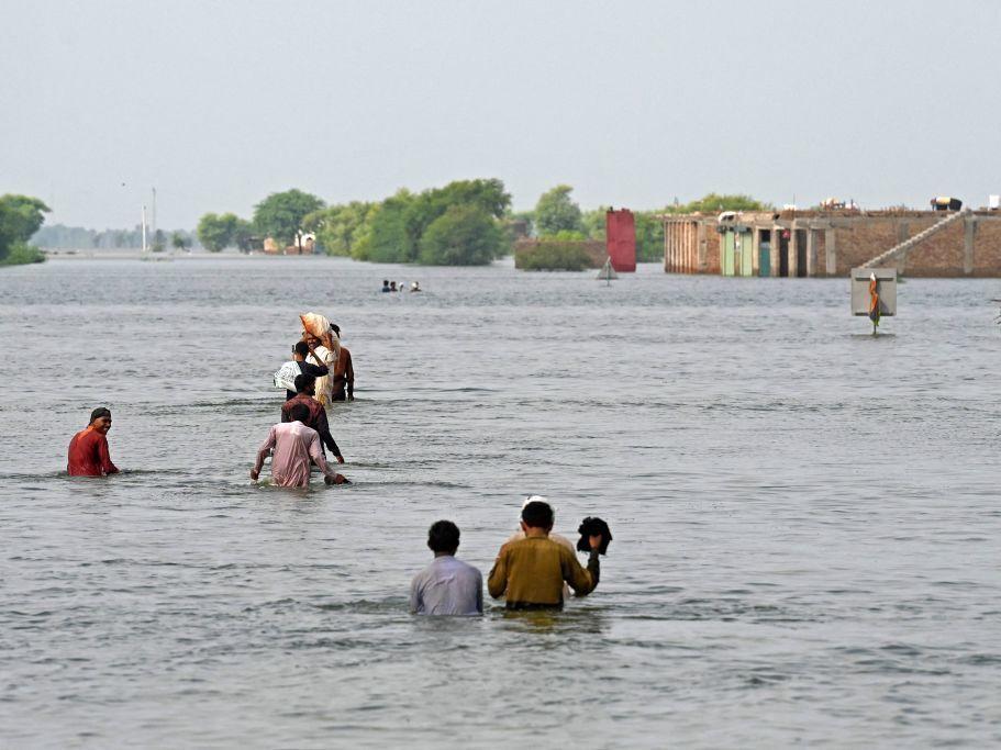 People wade through floodwaters in Pakistan after heavy monsoon rains this summer. Scientists say climate change helped drive the deadly floods.