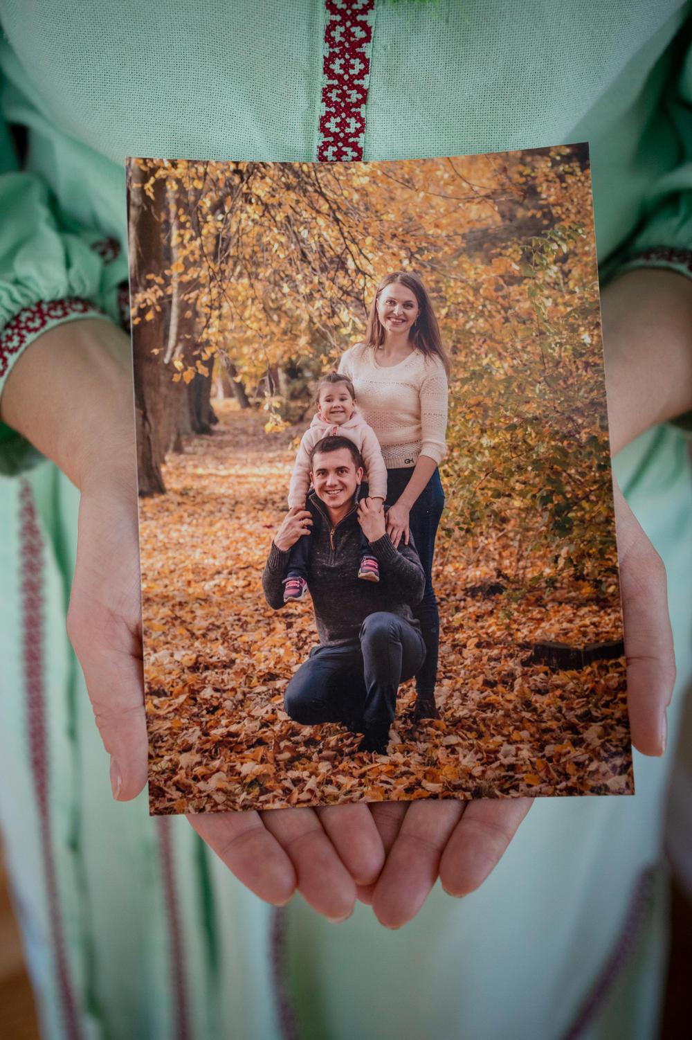 Olha Abakumova and her daughter Zlata, 8, recently immigrated to the U.S. from Ukraine. She's holding a family photo that shows her husband, Ihor, a tubaist with a symphony orchestra, who remains in Ukraine. Men ages 18 to 60 are as a rule not able to leave because they may be needed for military service.