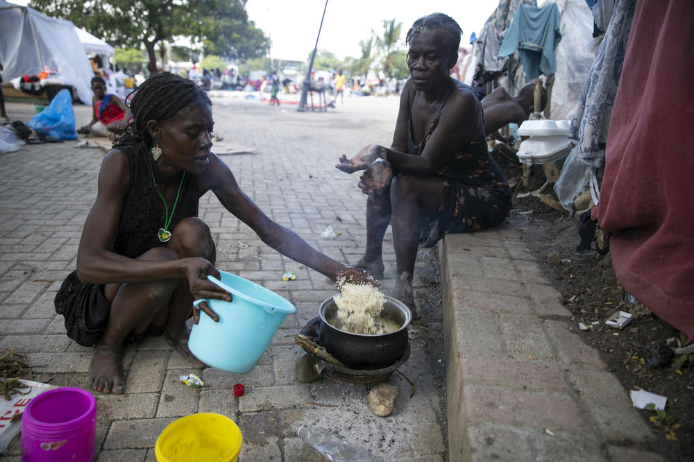 August Nerlande, left, cooks at the Hugo Chávez public square in Port-au-Prince on Oct. 22.