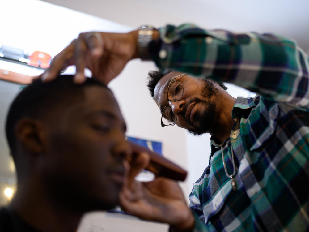 Talib Abdul Mujib, owner of barber shop 1617, shapes up a customer's hair line in the North Philadelphia neighborhood of Philadelphia on Friday, October 21, 2022. Mujib tells NPR that he does not plan on voting in the larger races — as he feels as though politicians don't value opinions of Black voters.