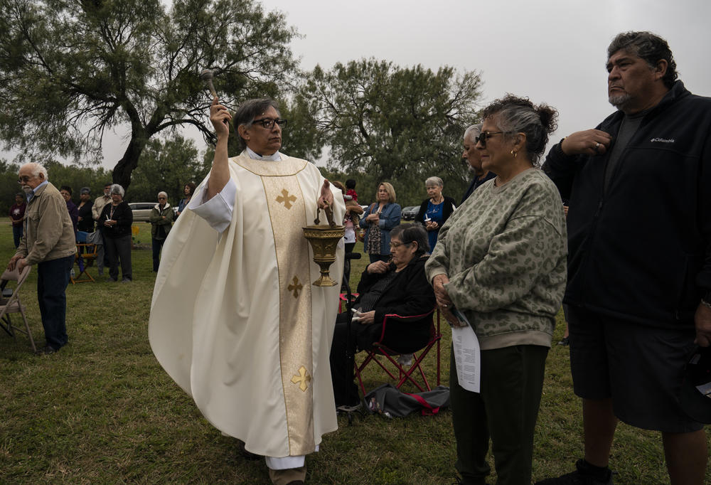 Priest Eddy Morales blesses people with holy water during the All Souls Day mass at Hillcrest Memorial Cemetery