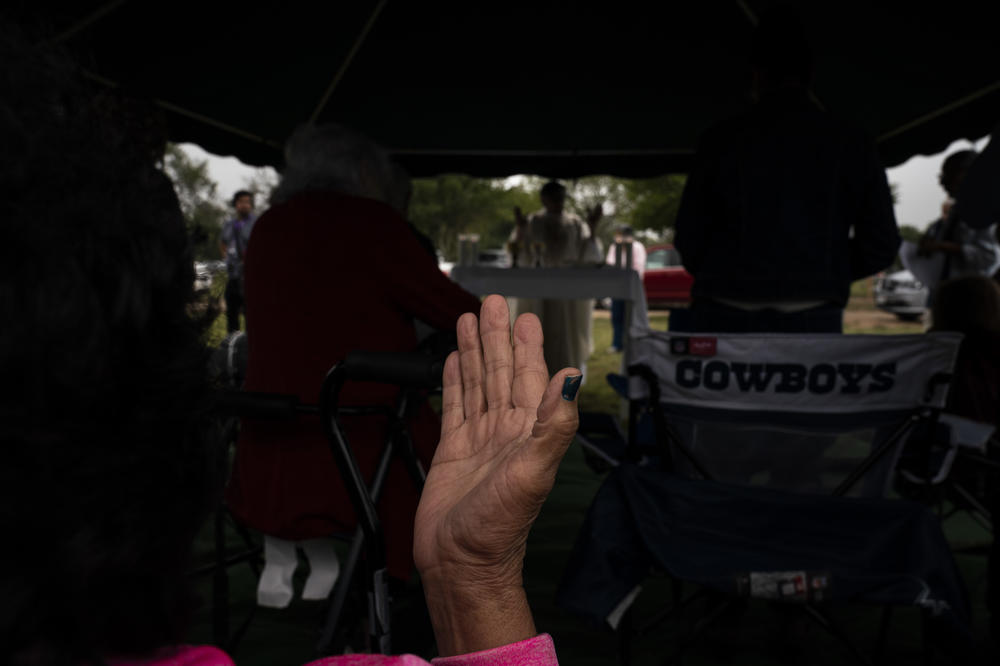 A woman prays during an All Souls Day mass at Hillcrest Memorial Cemetery on Wednesday, Nov. 2, 2022 in Uvalde, Texas.