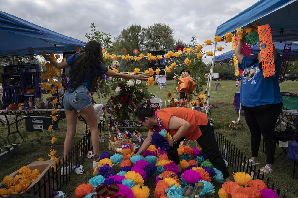Amber Alaniz, 21, left, Juanita Cázares, center, and Polly Alaniz, cousins and aunt of Jackie Cázares, help decorate her grave on Day of the Dead on Nov. 2, 2022 in Uvalde, Texas.