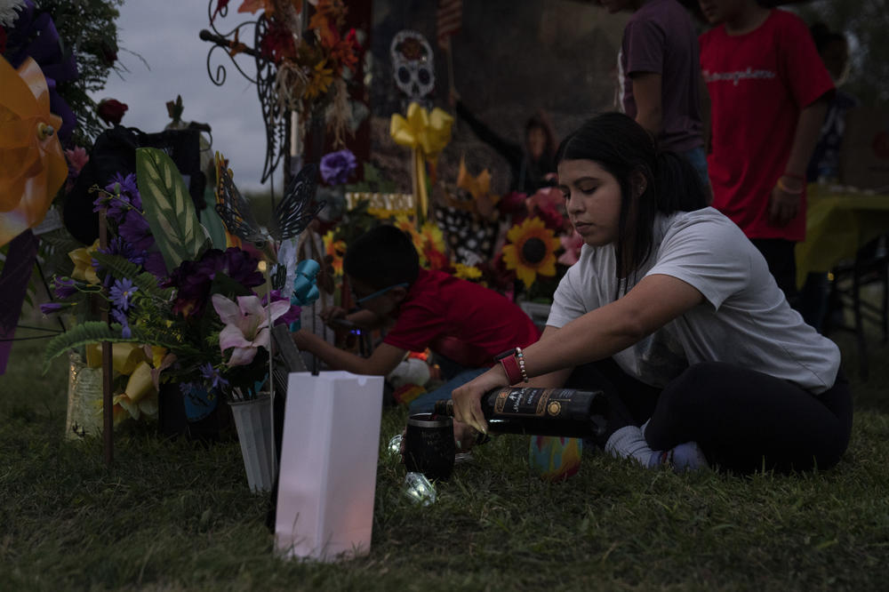 Adalynn C. Ruíz, 23, Eva Mireles' daughter, serves her mother's favorite wine in front of her grave.