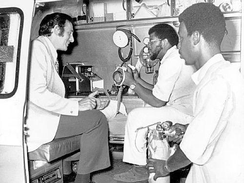 Paramedics Eugene Key and Harold Brown demonstrate their equipment for a guest in 1975.