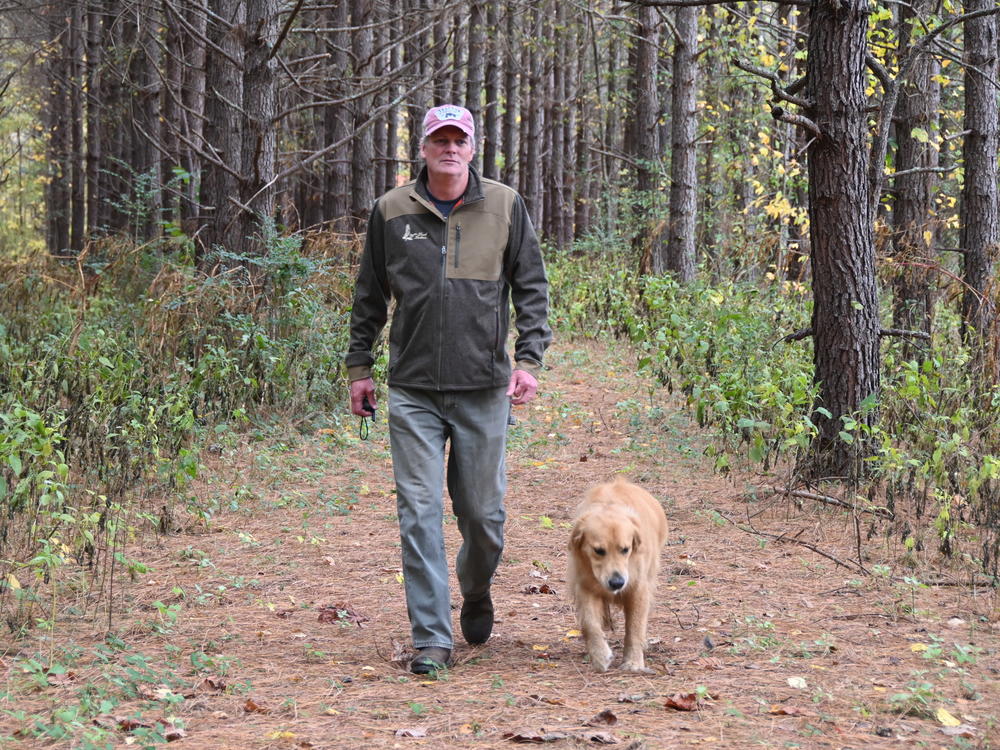 Warren Snowden walks on his family farm in Gaston County, N.C., with his dog Finn on Oct. 29, 2022. The property borders the site of a 1,500-acre lithium mine planned by Piedmont Lithium. He is helping to lead an opposition group called Stop Piedmont Lithium.