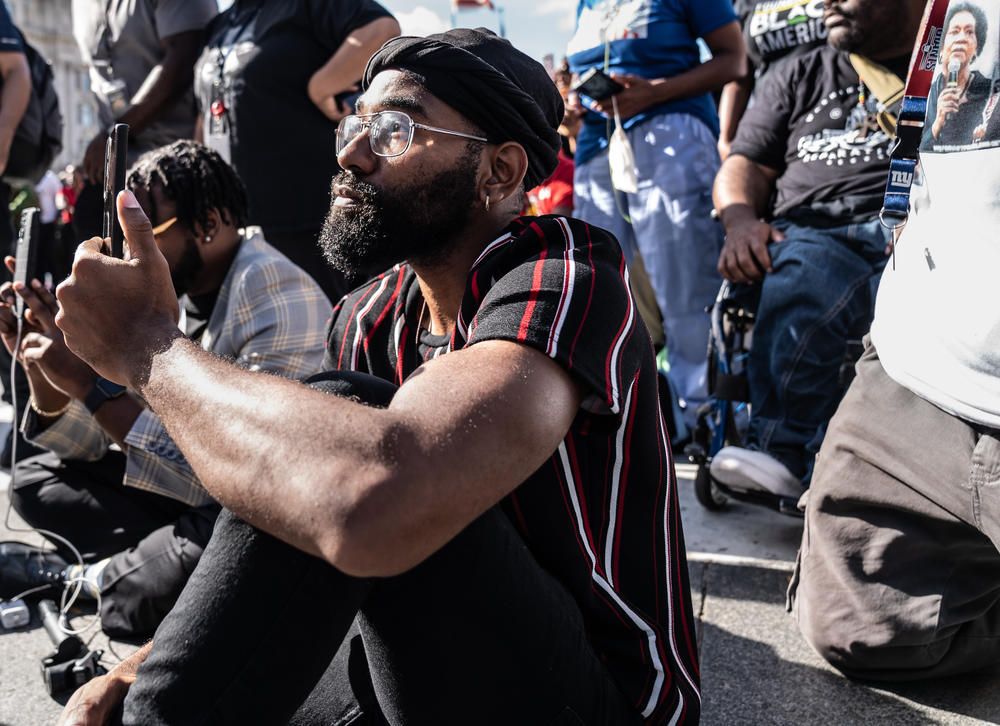 A Rally 4 Reparations attendee listens as host Tariq Nasheed speaks on the importance of reparations.