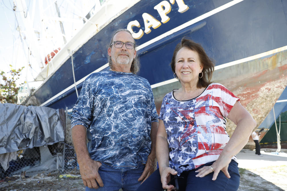 Roger Schmall, left, owner of the Kayden Nicole shrimping boat and Christine Gala, owner of Trico Shrimp Company, pose for a portrait at the shrimp fishing docks in Fort Myers, Fla., on Oct. 28, 2022. Schmall's boat is totaled though he's salvaging some parts to sell individually.