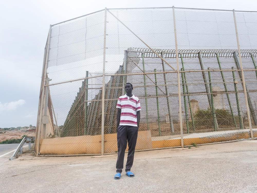Steven Khon Khon, of South Sudan, stands on the Spanish side of a four-layered fence dividing Nador, Morocco from Melilla, Spain on October 11. On June 24, Khon Khon and many others trying to get to Europe charged the fence. They were beaten back by Moroccan authorities. Dozens were killed. Khon Khon made it to Spain that day, but his brother remained stuck in Morocco.
