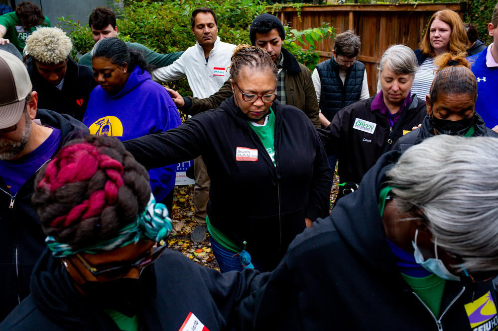 Shunda Whitfield, 53, of Rolling Acres, Mo., center, prays alongside supporters of Board of Aldermen presidential candidate Megan Green, on Saturday, Nov. 5, 2022, during a Get Out To Vote rally at Green's campaign headquarters in St. Louis' 