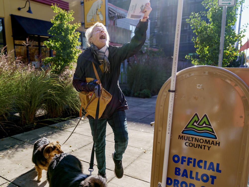 Perrin Thompson kisses her ballot for luck and does a little dance before dropping it into a drop site outside of the Multnomah County Elections Division in Portland, Ore., Nov. 8, 2022.