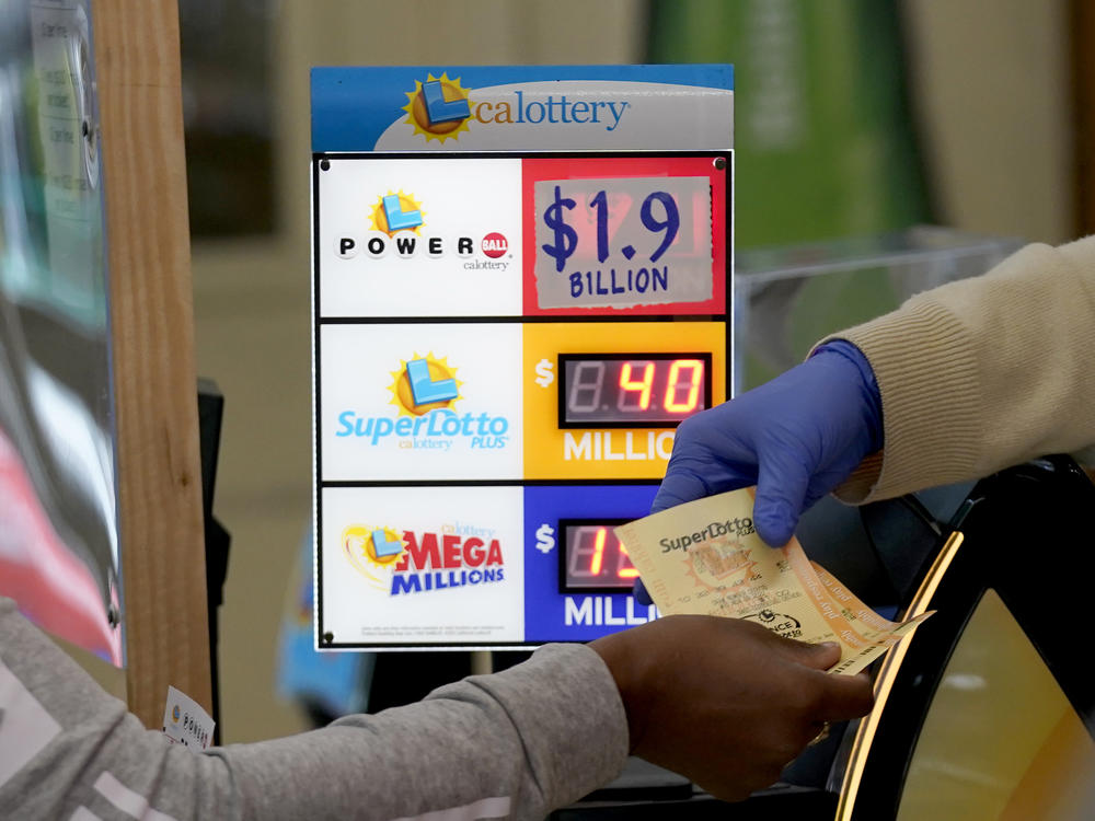 A customer is handed Powerball tickets purchased at Lichine's Liquor & Deli in Sacramento, Calif., Monday, Nov. 7, 2022. Monday night's drawing is estimated to be a record $1.9 billion.
