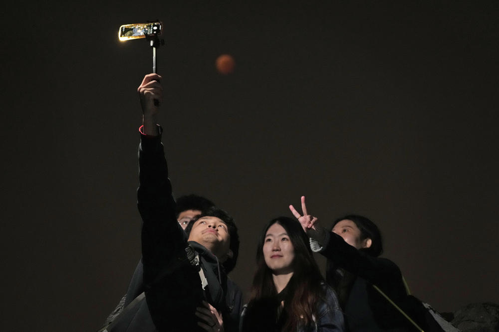 A group of friends in Beijing pose for a selfie as the moon rises during the lunar eclipse.