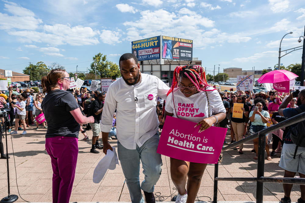 Democratic candidate for U.S. Senate Charles Booker walks with his eldest daughter, Kaylin Booker, during a press conference after addressing the Supreme Court's decision in the <em>Dobbs v. Jackson.</em>