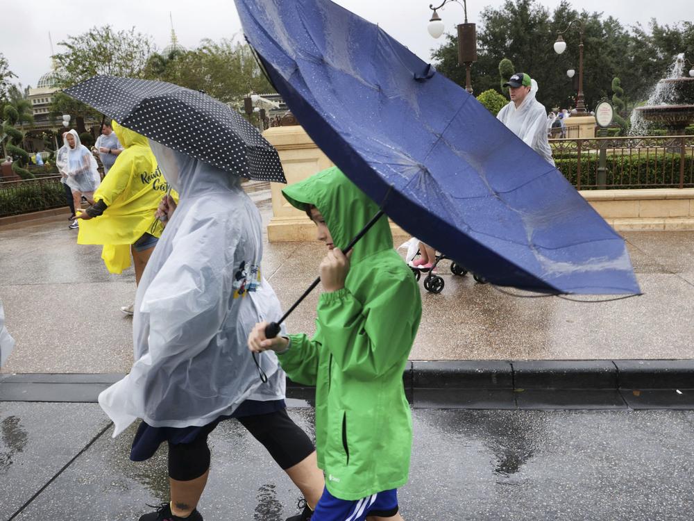 Winds blow an umbrella inside-out as guests leave the Magic Kingdom at Walt Disney World in Lake Buena Vista, Fla., Wednesday, Nov. 9, as conditions deteriorate with the approach of Hurricane Nicole.