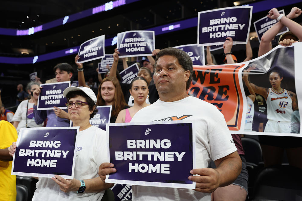 Supporters hold up signs reading 
