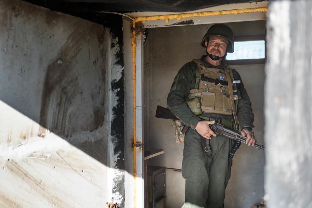 A soldier stands in a carefully sealed and covered room, heated by wood, at a position north of Kharkiv.