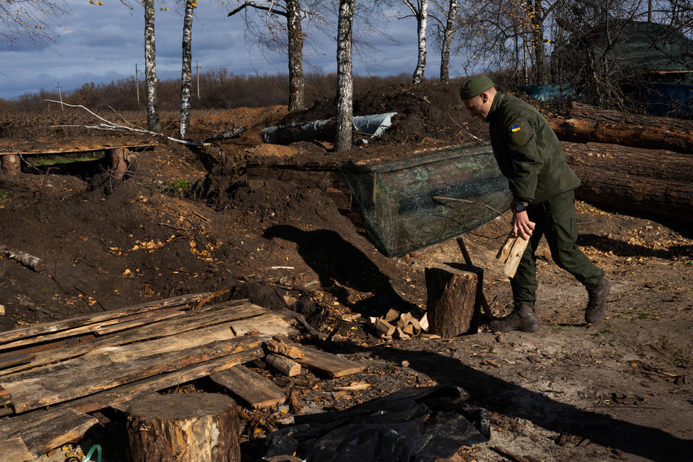 A soldier moves wood to chop for heating in the trenches in Kharkiv region.
