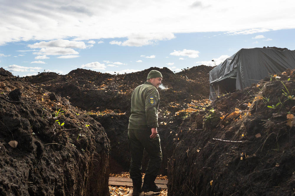 A soldier in Kharkiv region walks through a trench, his breath showing in the cold air.