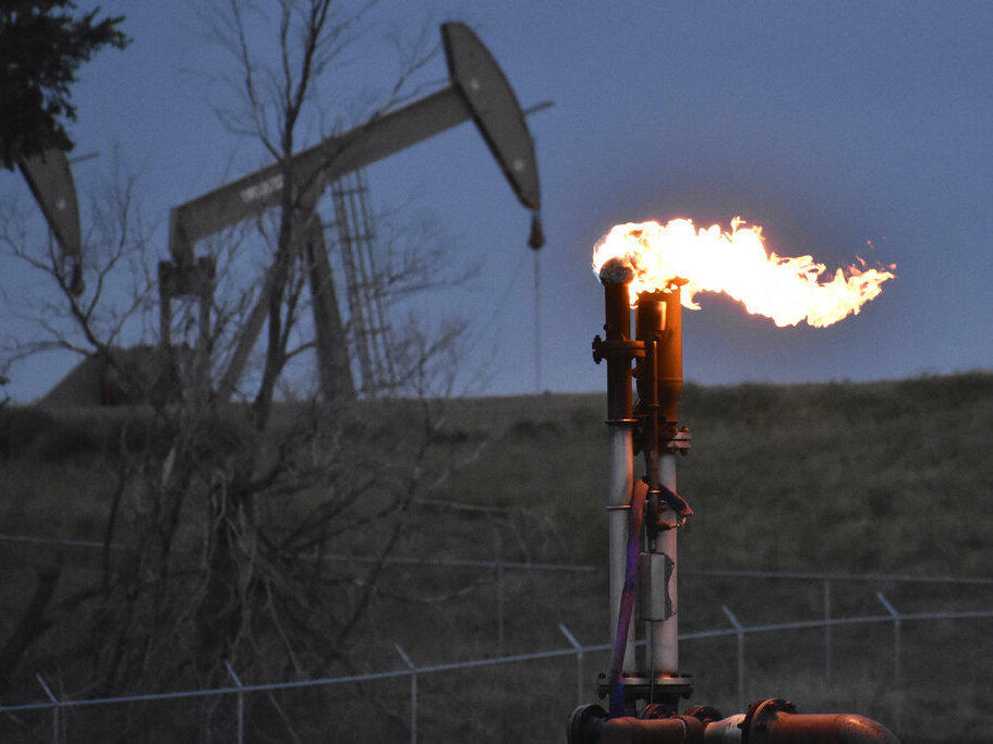 A flare to burn methane from oil production is seen in August 2021 on a well pad near Watford City, N.D.