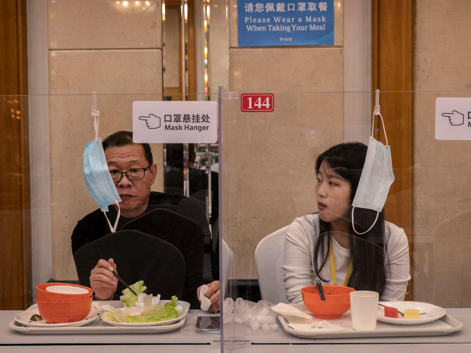 People eat lunch separated by plexiglass to prevent the spread of COVID-19 at the 20th National Congress of the Communist Party of China on Oct. 20 in Beijing. China is beginning to ease its strict COVID policies to help the stifled economy.