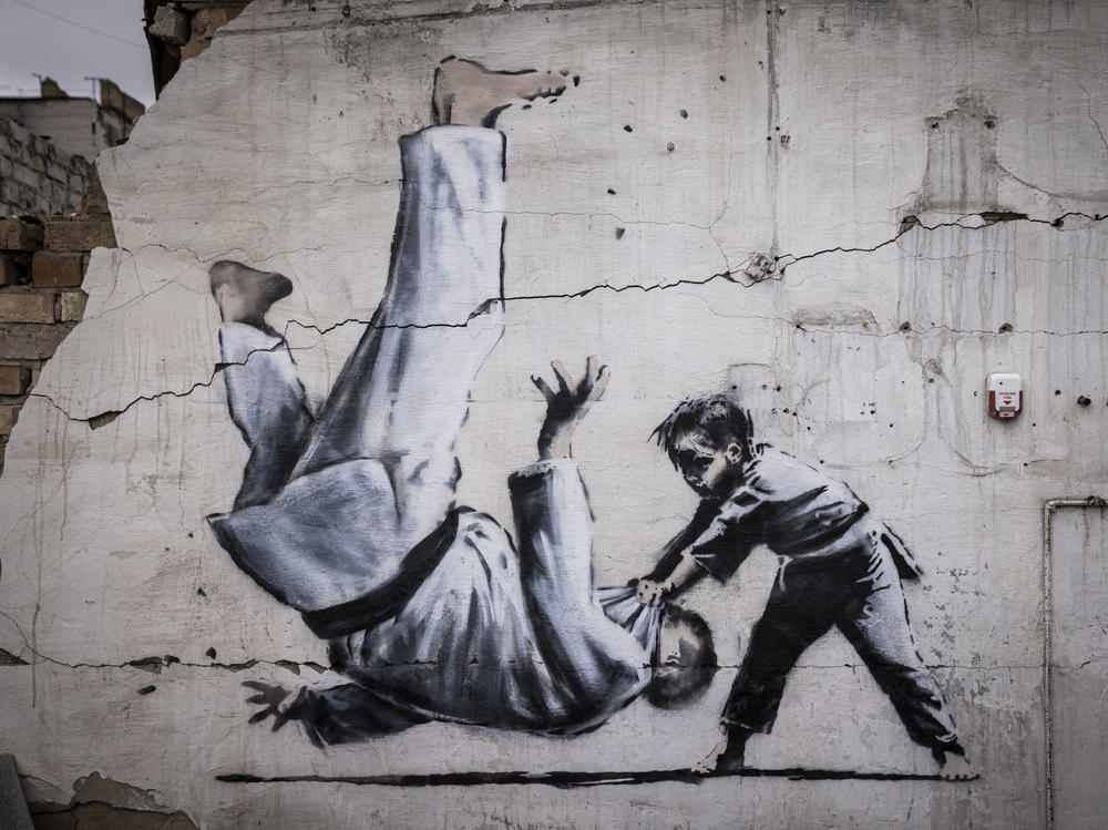 Graffiti of a child throwing a man on the floor in judo clothing is seen on a wall amid damaged buildings in Borodyanka on Friday.