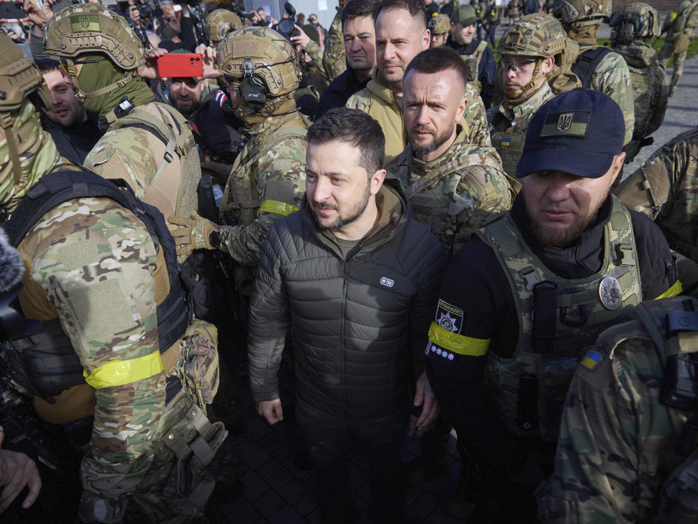 In this photo provided by the Ukrainian Presidential Press Office, Ukrainian President Volodymyr Zelenskyy, surrounded by his guards, walks on central square during his visit to Kherson on Monday.
