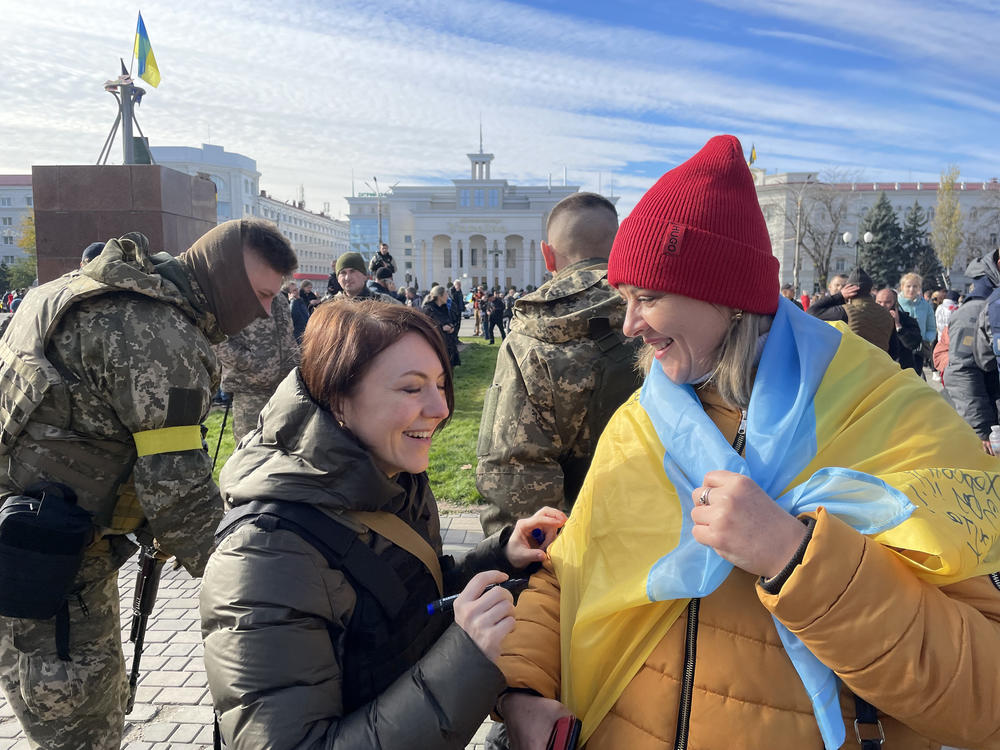 Hanna Malyar, Ukraine's deputy defense minister (center), signs a Ukrainian flag belonging to a local resident in Kherson on Monday. 