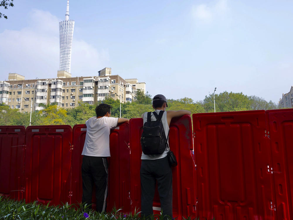 Residents look out from barriers around the recently locked down Haizhu district in Guangzhou in southern China's Guangdong province Friday, Nov. 11, 2022.