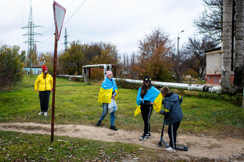 Local youth drape themselves in Ukrainian flags in recently liberated Kherson on Wednesday.