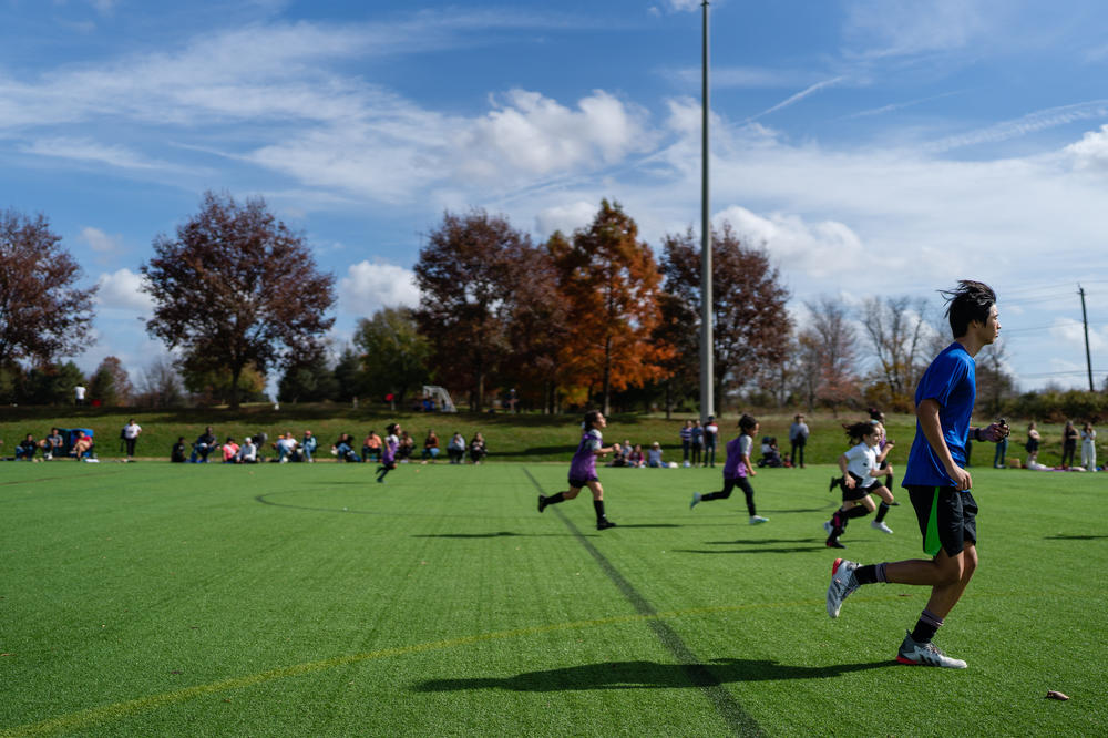 Jason Kim a new referee being mentored by Peter Guthrie runs to follow a play during a youth soccer match.