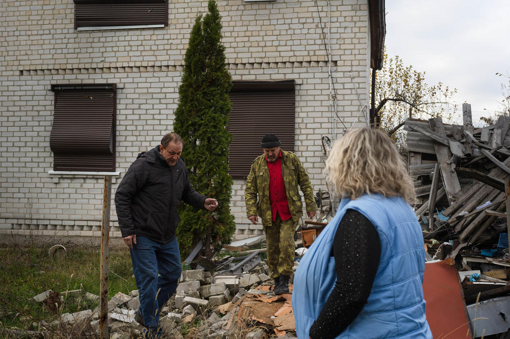 Voinov with Oleksandr Lysytskyi and his wife, Svitalana Maliarova, look at rubble in their neighborhood. They are some of the few residents staying in their village where power is expected to be out for months.