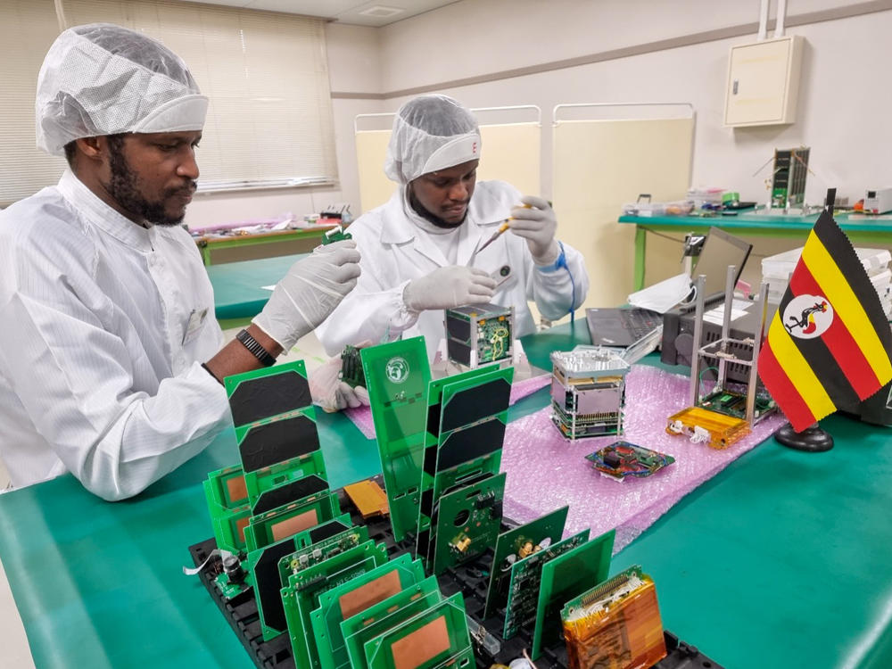 Bonny Omara (left) works with Edgar Mujuni at Japan's Kyushu Institute of Technology on the satellite that will be used to observe land conditions in Uganda.