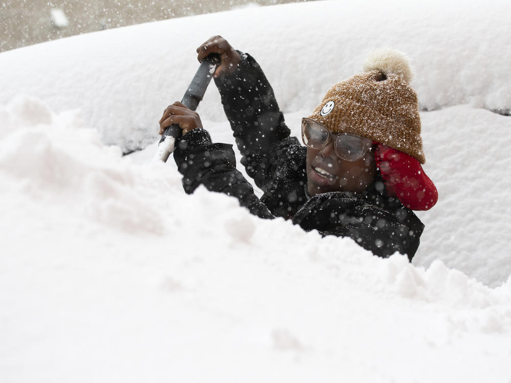 Zaria Black, 24, from Buffalo, clears off her car as snow falls Friday, Nov. 18, 2022, in Buffalo, N.Y.