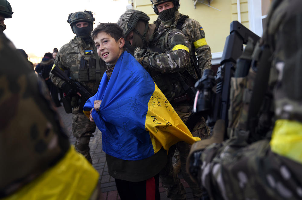 Soldiers sign a child's Ukrainian flag at the train station in Kherson.