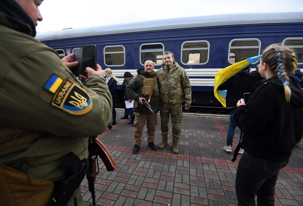 People pose for photos with Ukrainian singer Kolya Serga (right) on the train platform.